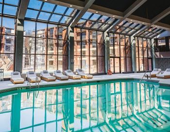 a swimming pool in front of a building with large windows